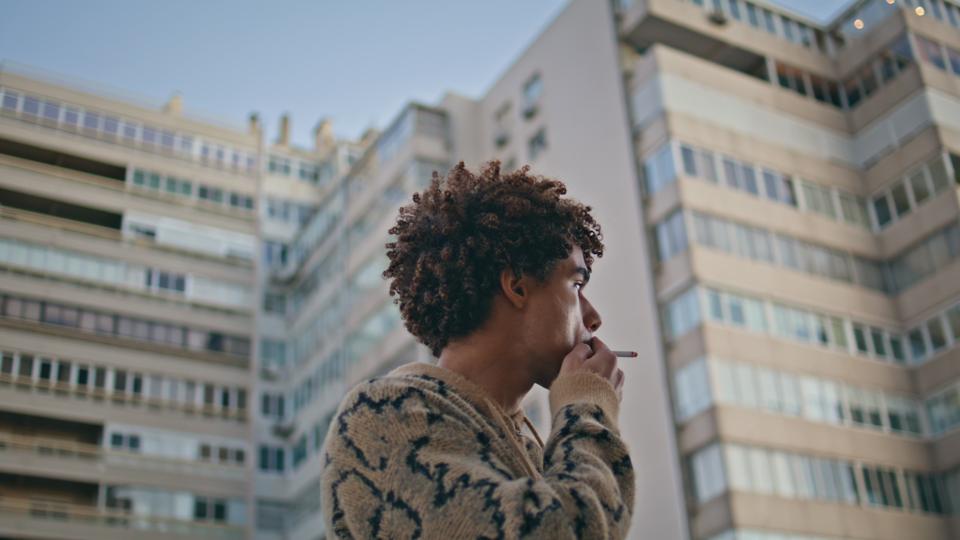 Thoughtful man smoking urban cityscape closeup. Pensive latin american hipster