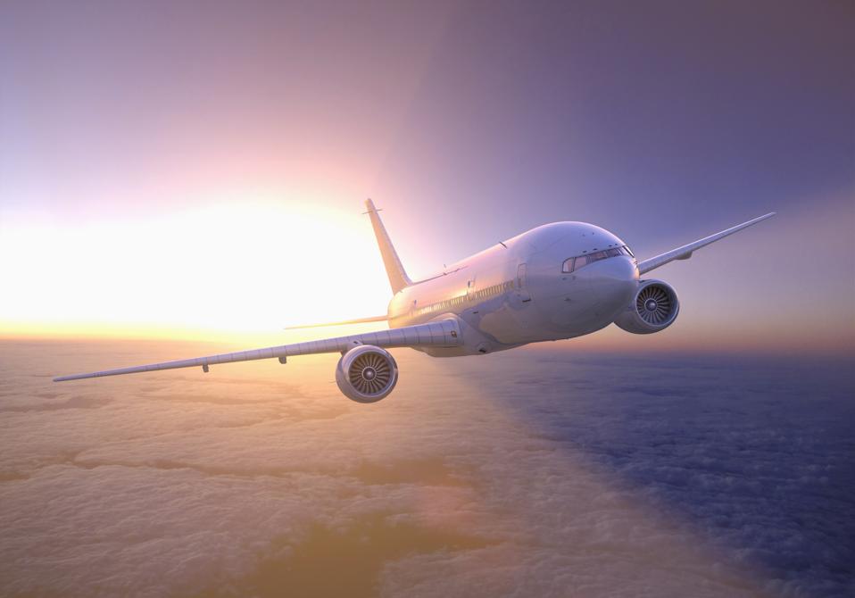 Airplane flying above clouds at sunset