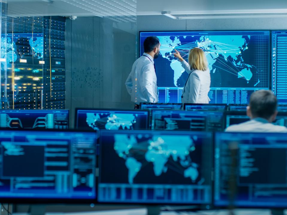 In the System Monitoring Room Two Senior Operators Work on a Big Interactive Map. Facility is Full of Screens Showing Technical Data.