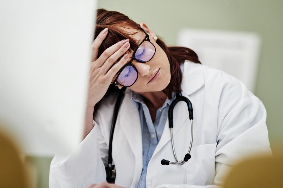 Shot of a young doctor looking stressed while using a computer at work
