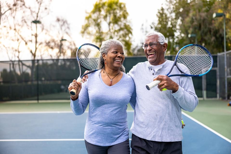 Pareja negra senior saliendo de la cancha de tenis