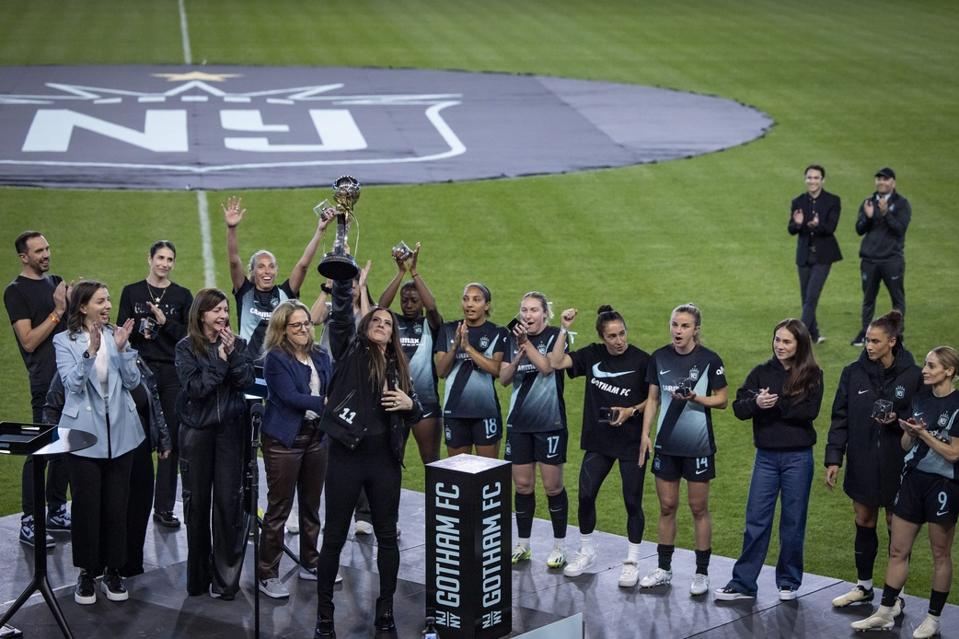 Ali Krieger, former NJ/NY Gotham FC captain, holds up the 2023 NWSL Championship trophy.