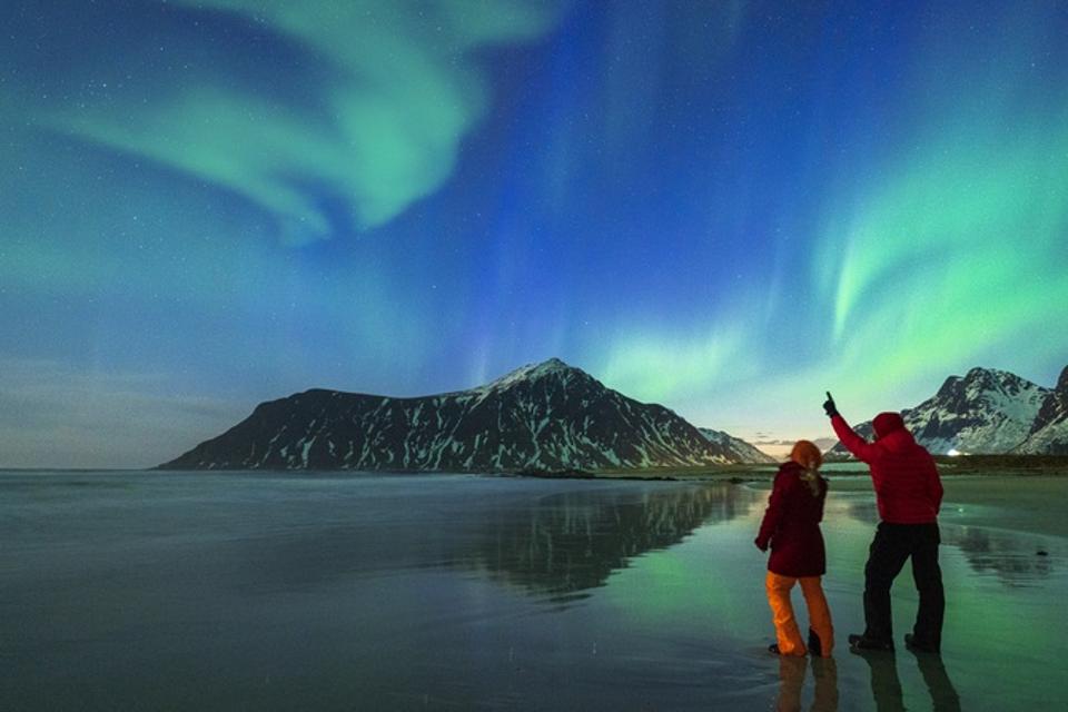 Man and woman watching Northern Lights from Skagsanden beach