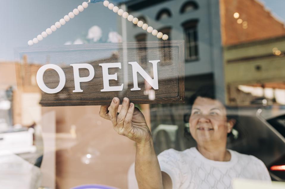 Shop Owner Turning Round Her 'Open' Sign In The Window
