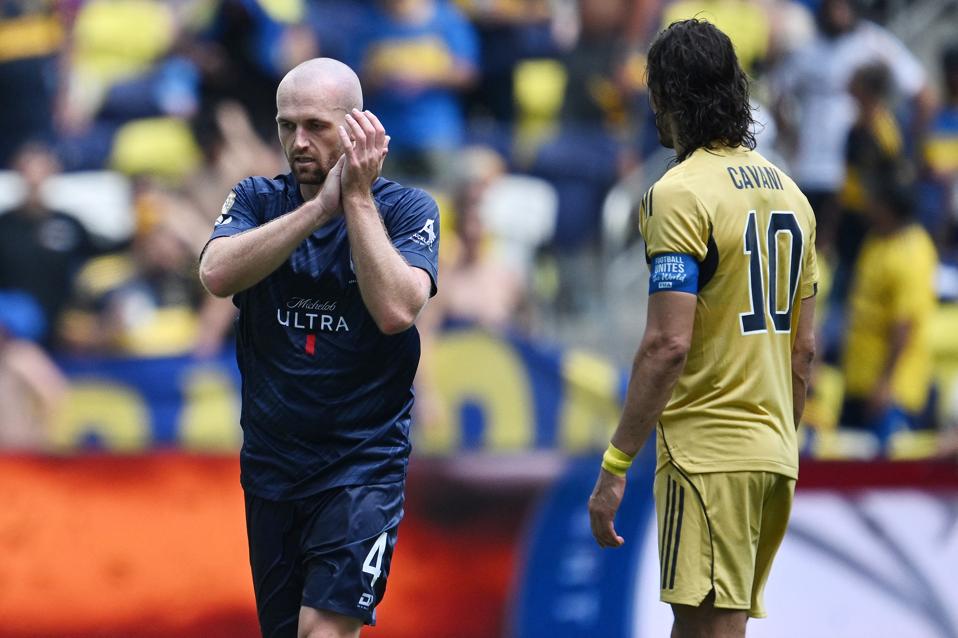 Auckland City player Christian Gray claps with Boca Juniors' Edinson Cavani next to him.