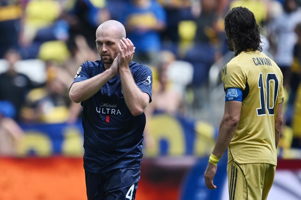 Auckland City player Christian Gray claps with Boca Juniors' Edinson Cavani next to him.