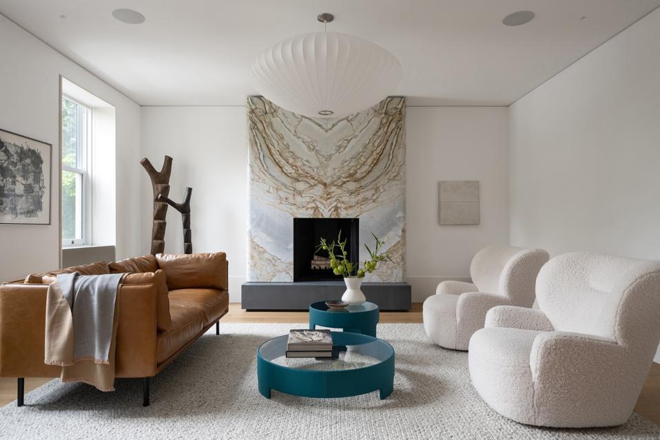 Living room with leather couch, two boucle chairs, and dramatic stone-look fireplace.