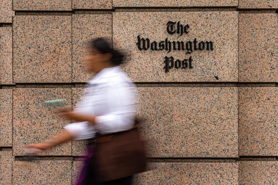 A woman walks in front of The Washington Post headquarters building