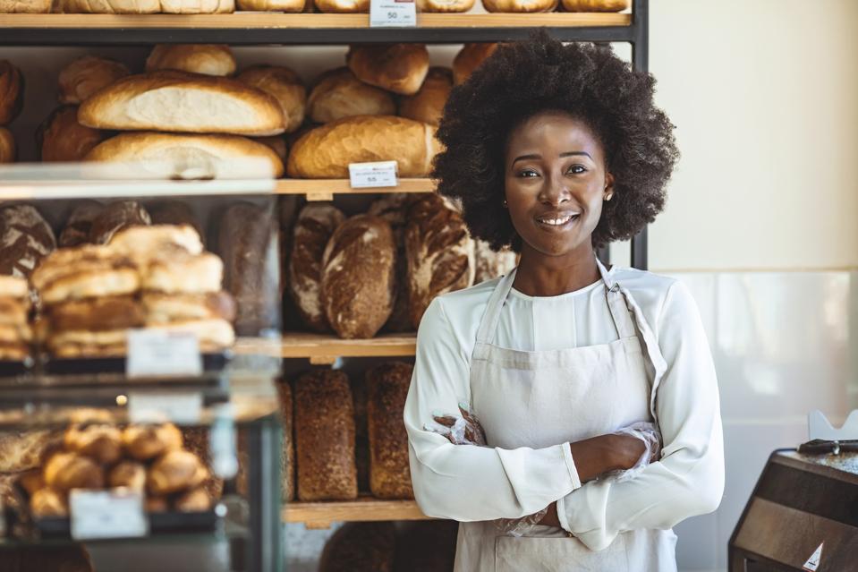 Small Bakery shop owner standing in front of store.