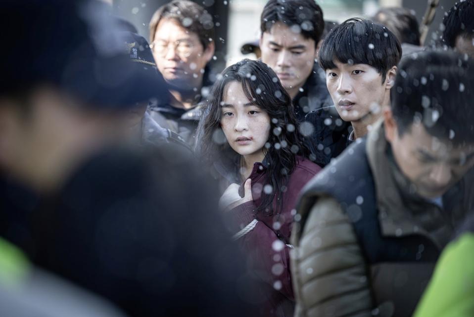 A woman is surrounded by policemen on a snowy day.