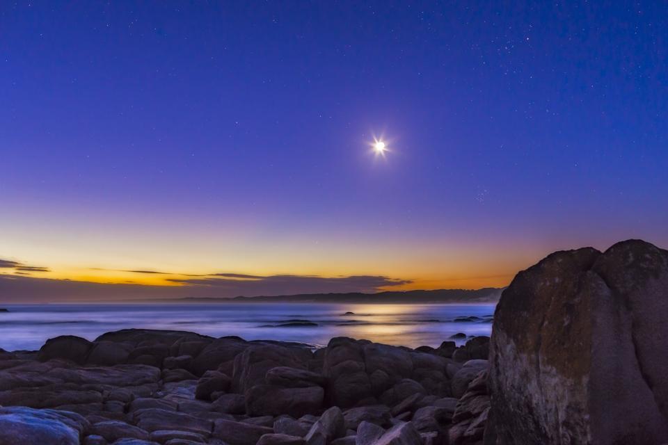 The waxing crescent Moon in deep evening twilight with stars beginning to appear