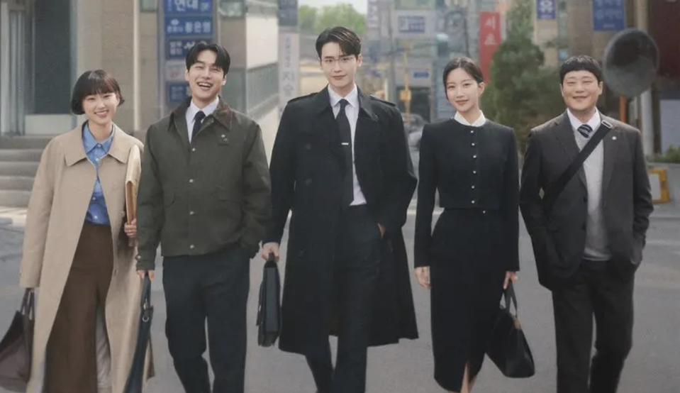 Three male lawyers and two female lawyers walk down the street.