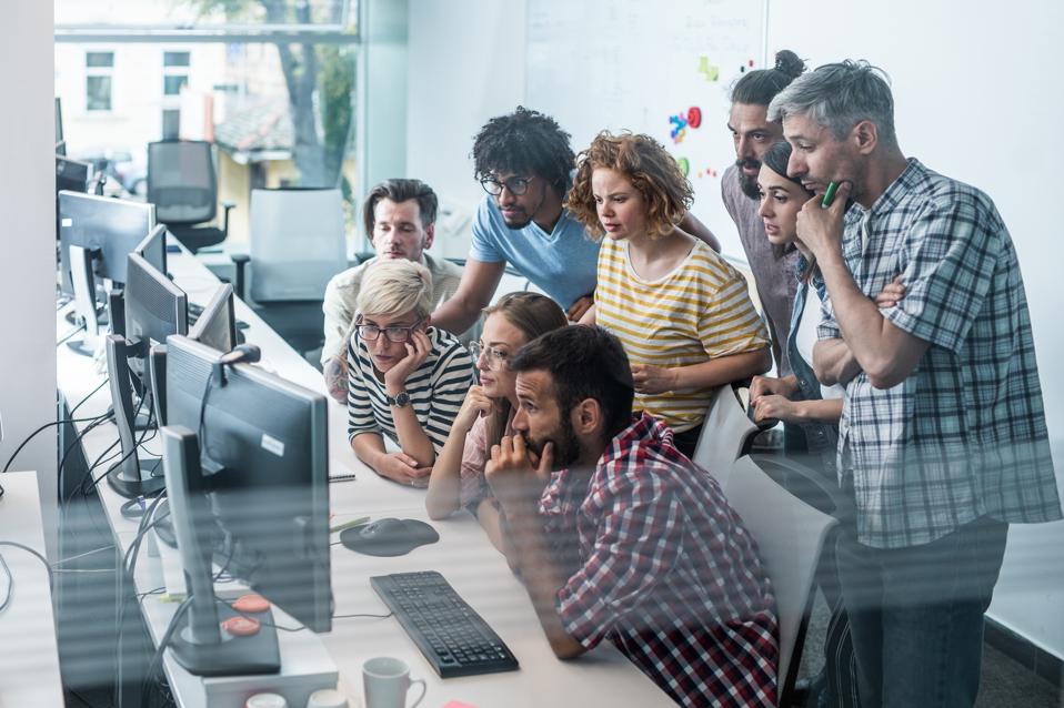 Team of worried computer programmers working on desktop PC in the office.