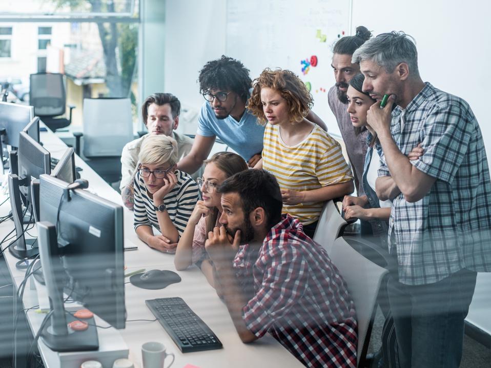 Team of worried computer programmers working on desktop PC in the office.