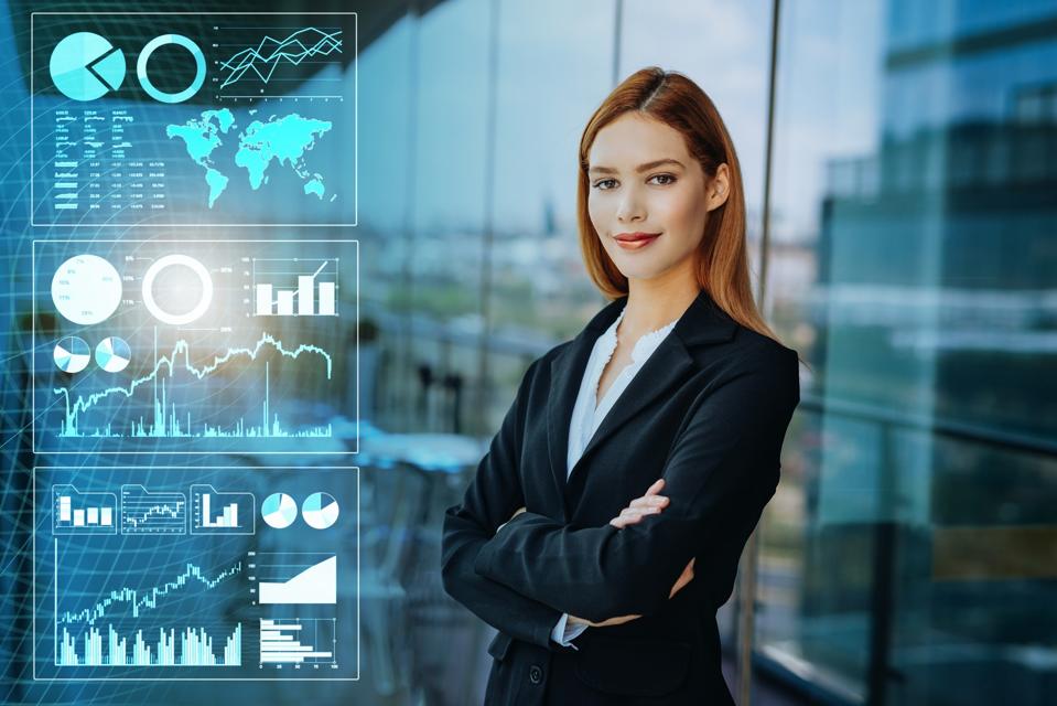 Businesswoman standing with arms crossed and looking at camera surrounded by digital graphics and financial data in a modern office setting, presenting artificial intelligence in business and finance