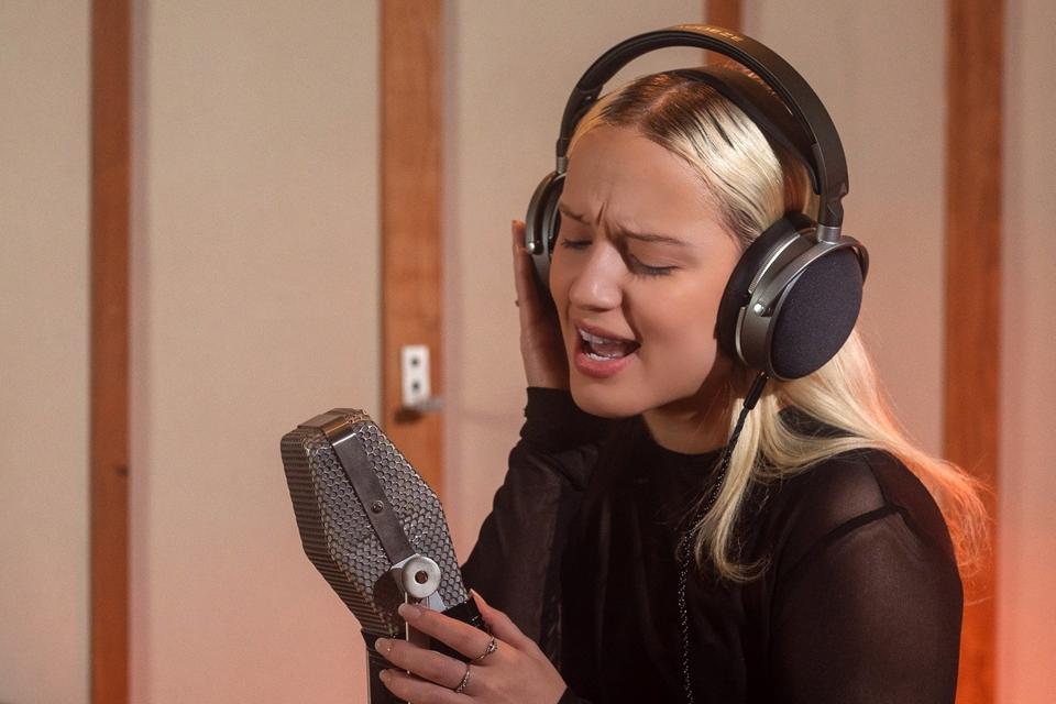 Woman wearing Audeze LCD-S20 headphones and singing into a microphone