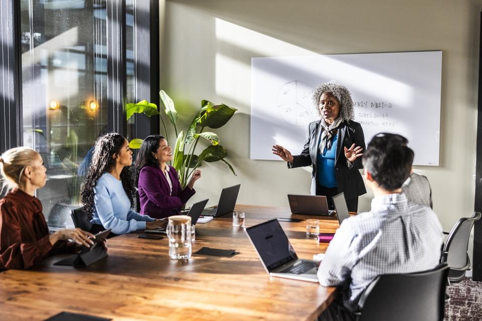 Female business owner speaking to office workers in modern conference room