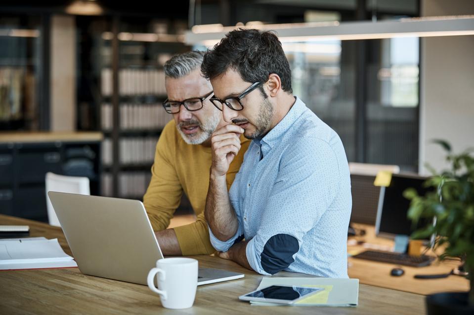 Businessmen using laptop at desk