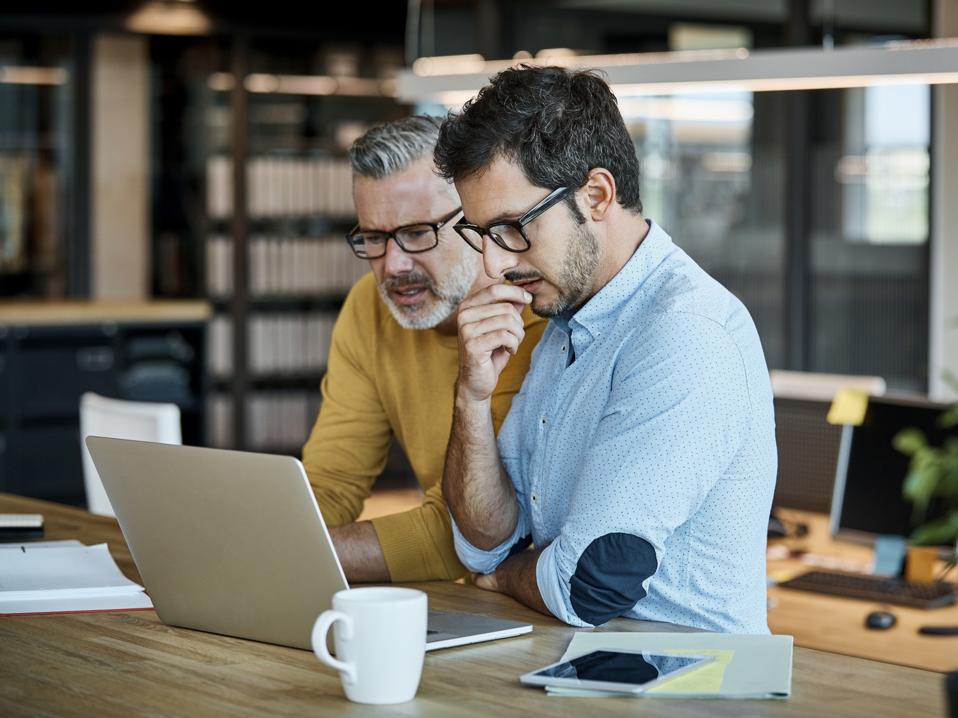 Businessmen using laptop at desk