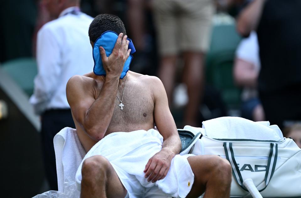 Novak Djokovic wipes his brow during his opening Wimbledon match against Alexandre Muller.