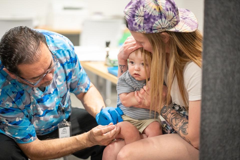 Infant held by mother receives a vaccine from a healthcare provider.