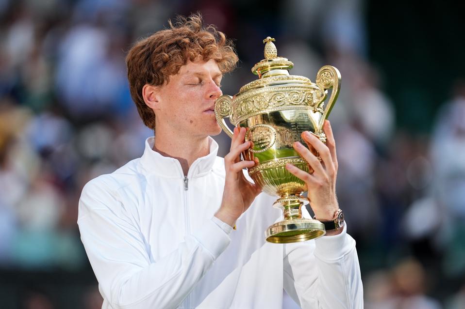 Jannik Sinner kisses the Wimbledon trophy after beating Carlos Alcaraz in the men's final.