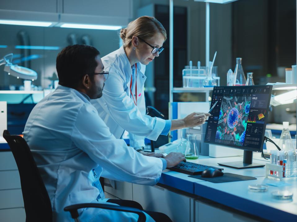 Female Research Scientist with Bioengineer Working on a Personal Computer with Screen Showing Virus Analysis Software User Interface. Scientists Developing Vaccine, Drugs and Antibiotics in Laboratory
