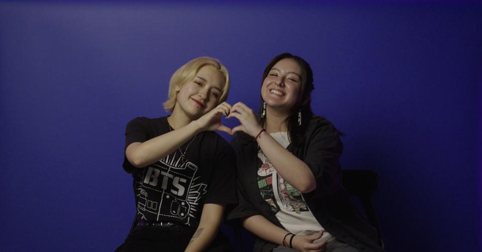 Two BTS fans make a heart sign.