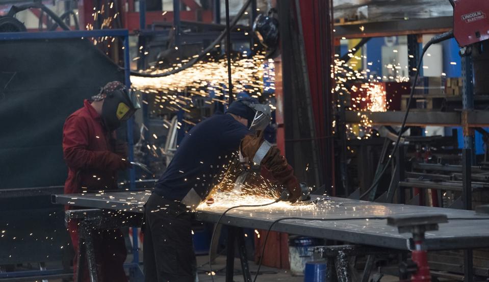 Workers in a factory working with metal on the shop floor.