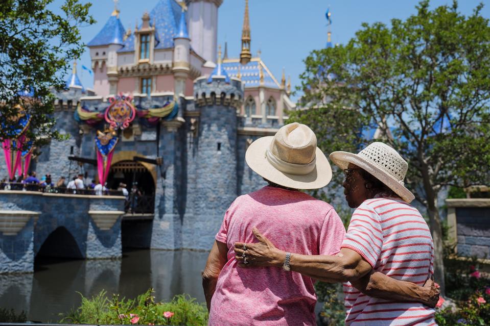 Two women standing in front of Sleeping Beauty Castle at Disneyland Park.