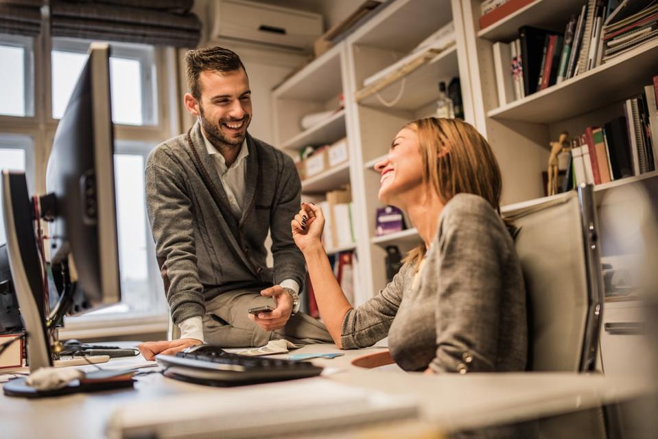 Jeunes collègues des affaires joyeuses qui flirtent au siège social.