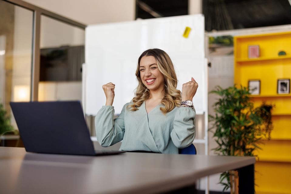 Excited businesswoman triumphing with fist up in office