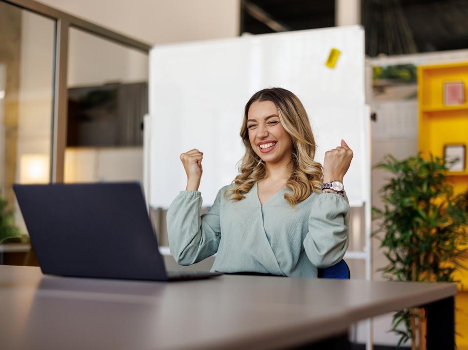 Excited businesswoman triumphing with fist up in office