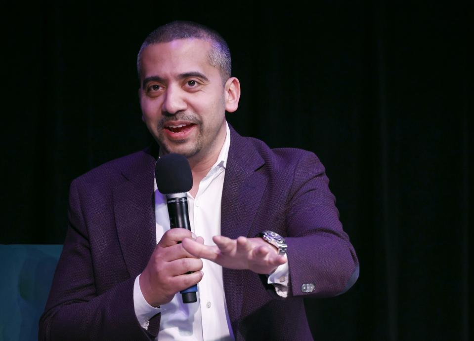 Mehdi Hasan holding a microphone and speaking onstage