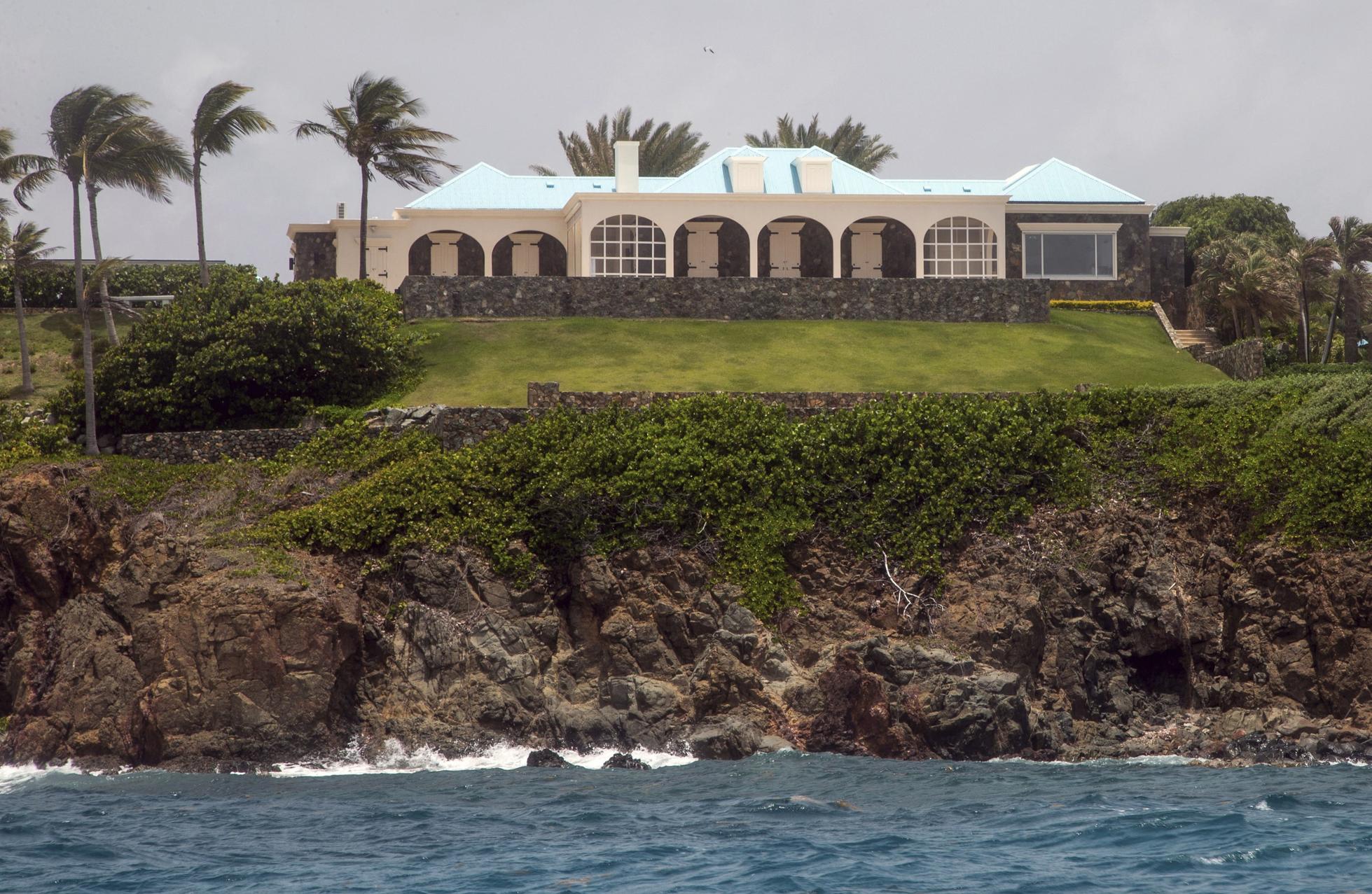A white estate fringed by palm trees behind a green lawn and rocky cliff on Little St. James Island, Jeffrey Epstein's former island in the U.S. Virgin Islands. 