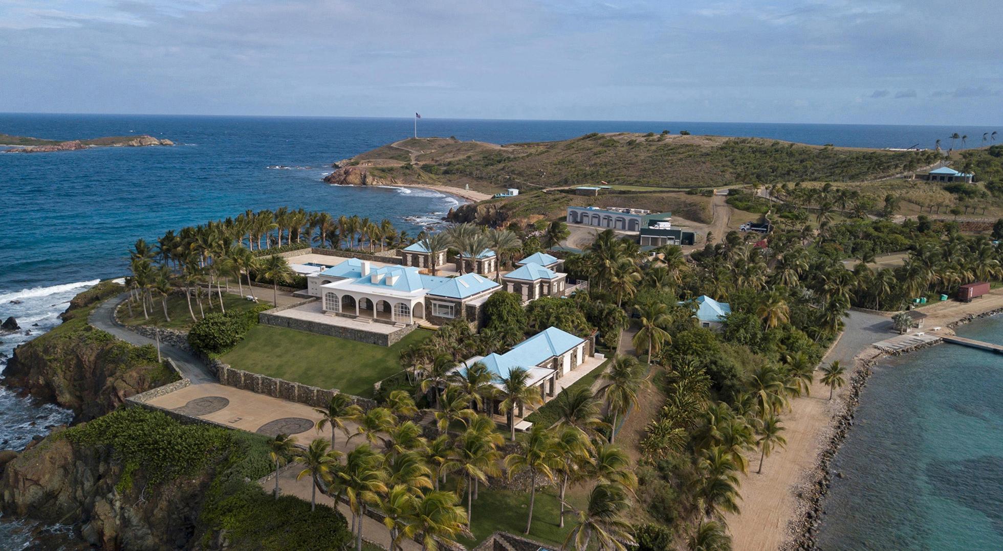 An island with a mansion in the foreground, surrounded by palm trees, formerly owned by Jeffrey Epstein, in the U.S. Virgin Islands.