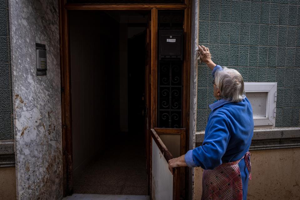 A gray-haired woman in an apron wipes an exterior wall
