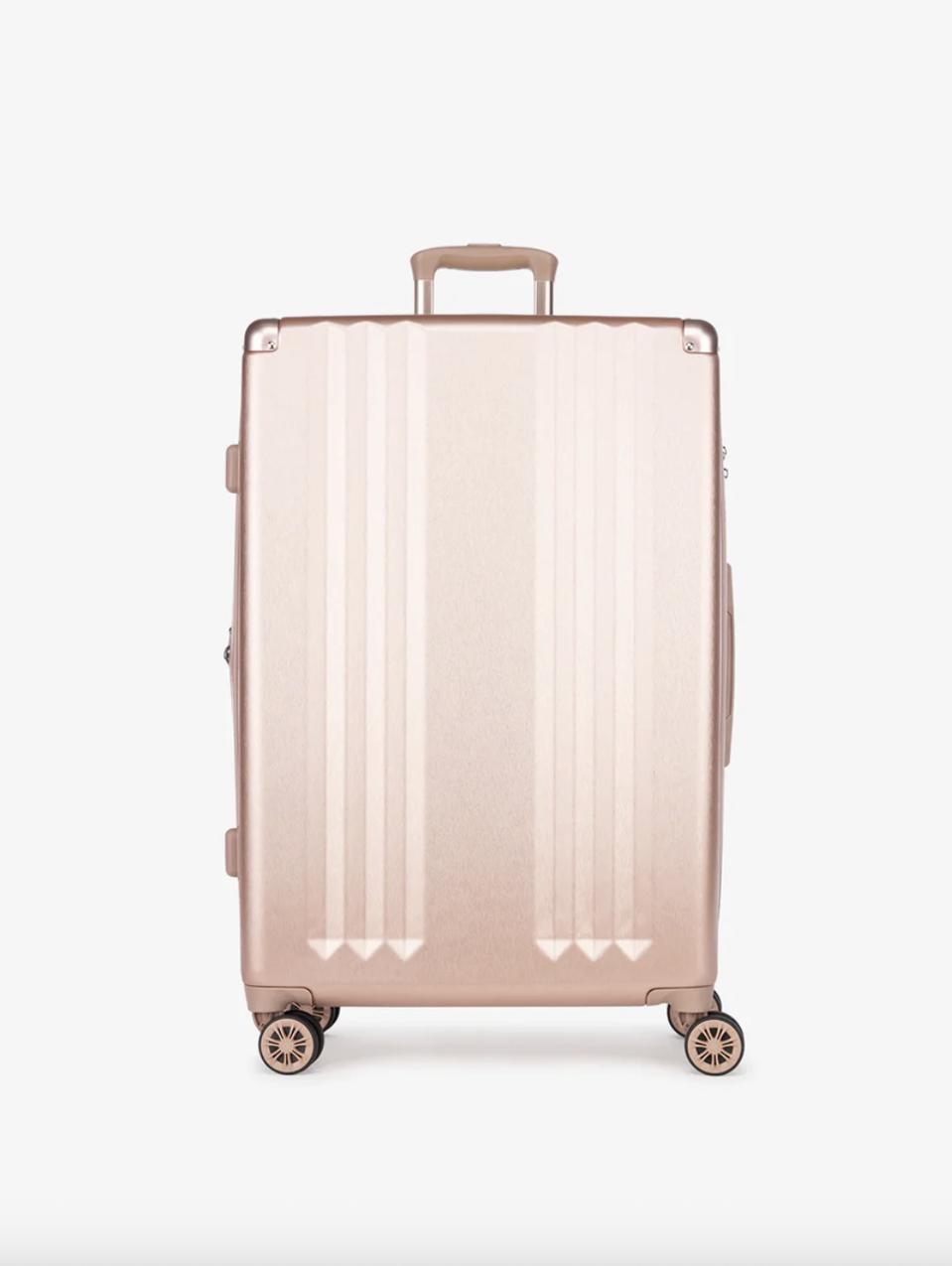 Rose Gold luggage against a white wall.