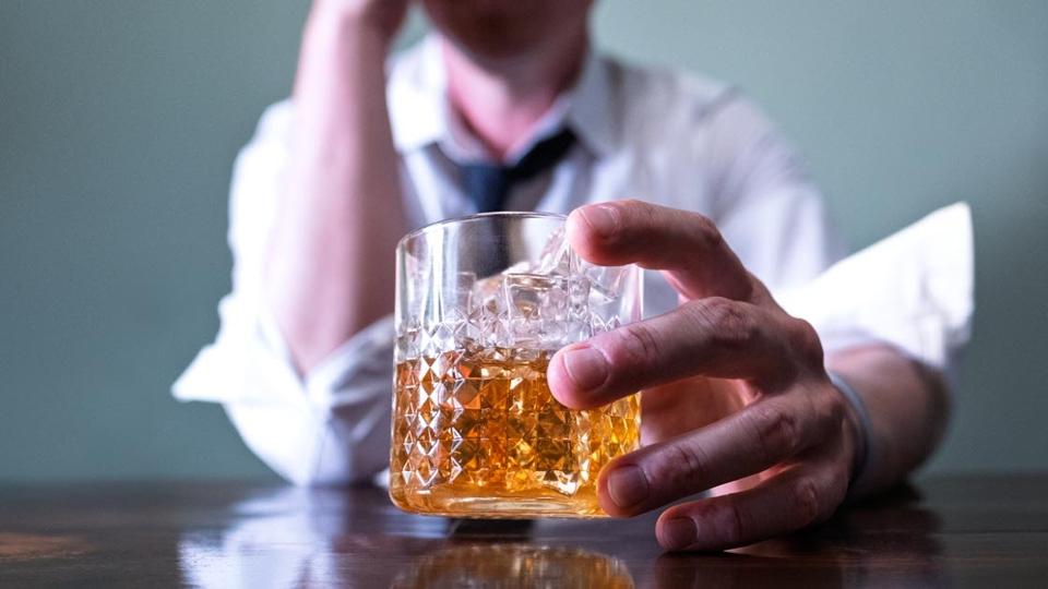cu photo of a man holding an alcoholic beverage.