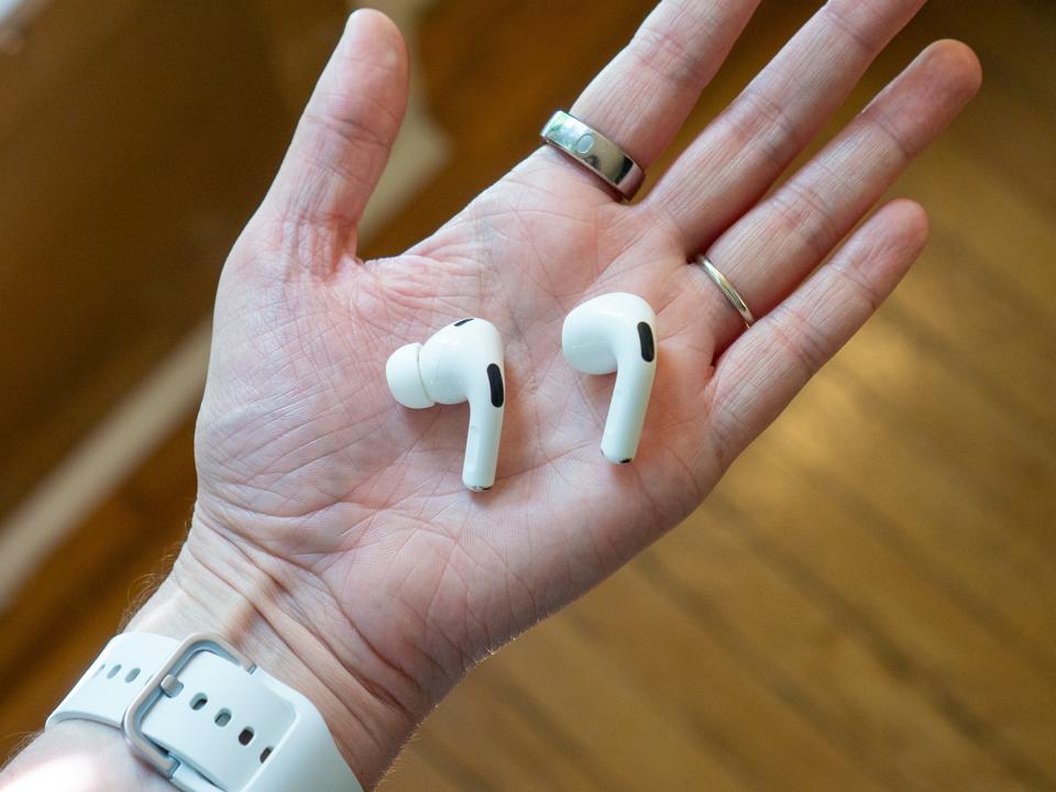 An Apple AirPod Pro 2 (left) and Apple AirPod 4 (right) held in a hand