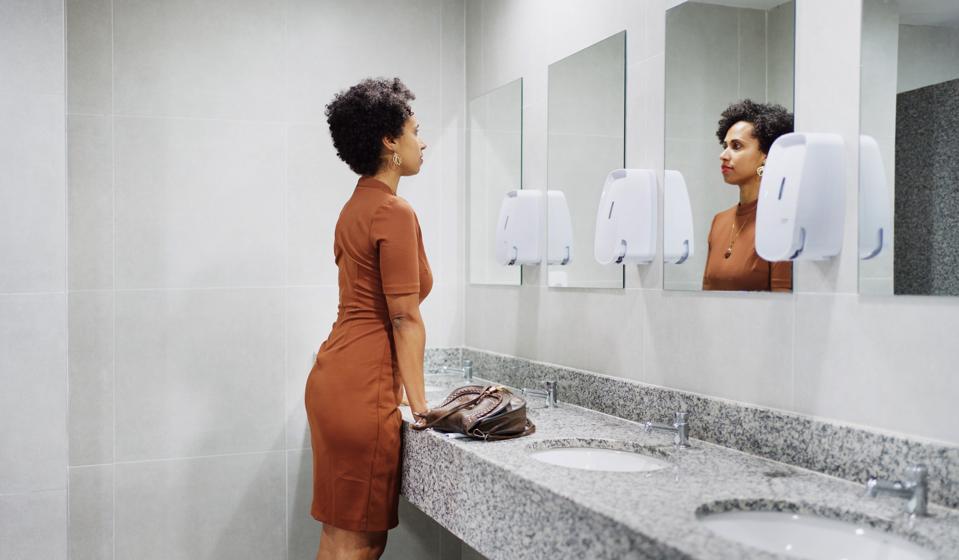 Businesswoman mentally preparing for speech in a office bathroom