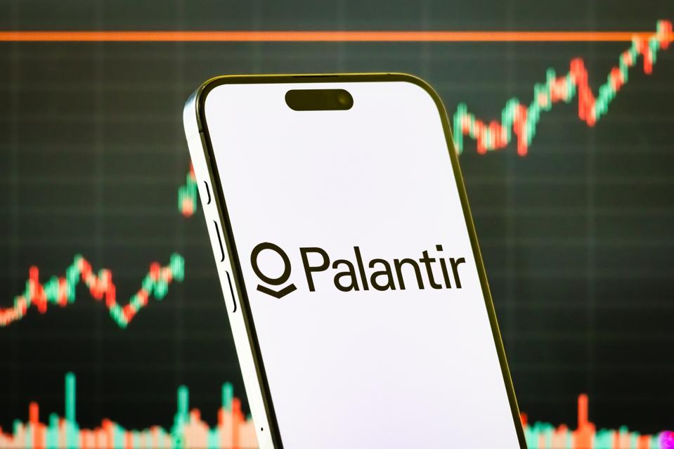 Palantir Technologies Inc. logo on smartphone with stock market chart background