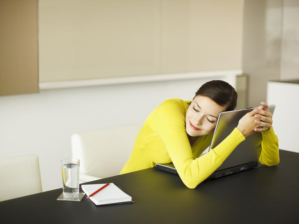 Smiling businesswoman hugging laptop in conference room