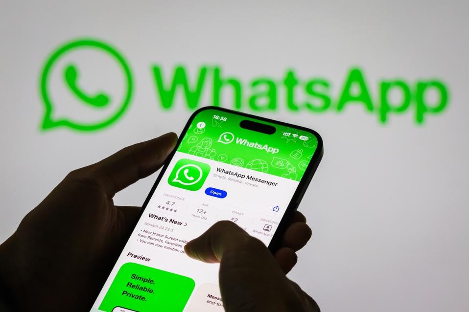 smartphone displaying the WhatsApp app page, with the WhatsApp logo in the background