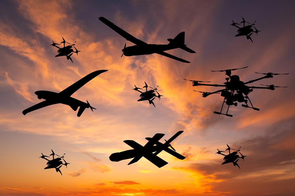 Different types of military unmanned aerial vehicles at sunset