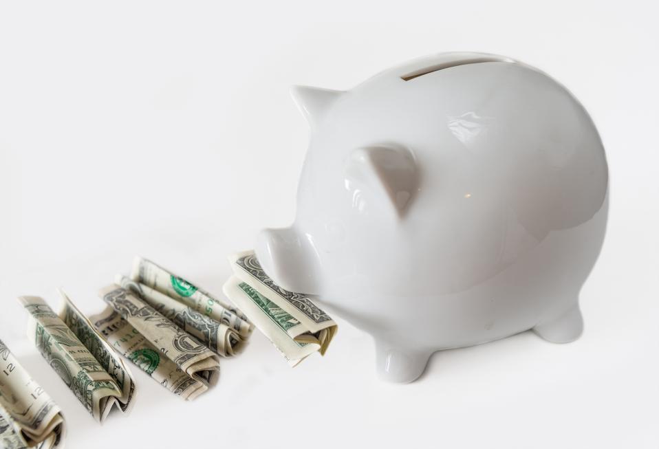 White piggy bank placed next to USA dollars