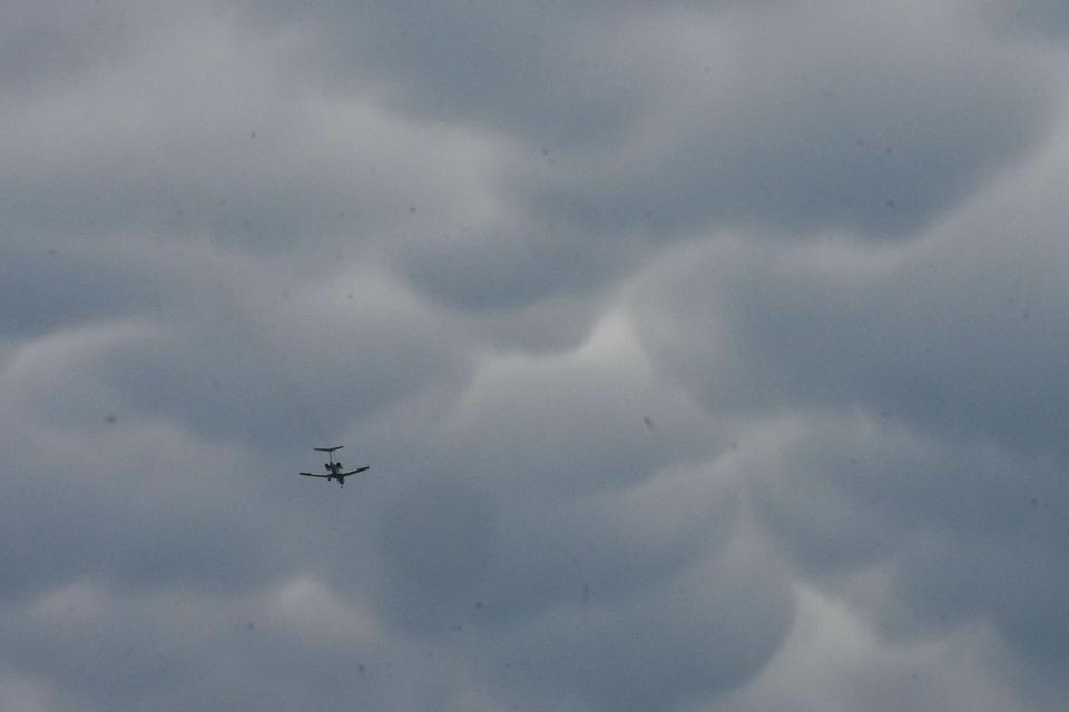 Plane flying below mammatus clouds