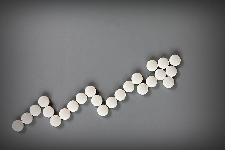 Vista superior o un lento plano de un creciente costo gráfico de medicamentos recetados sobre fondo gris con espacio de copia