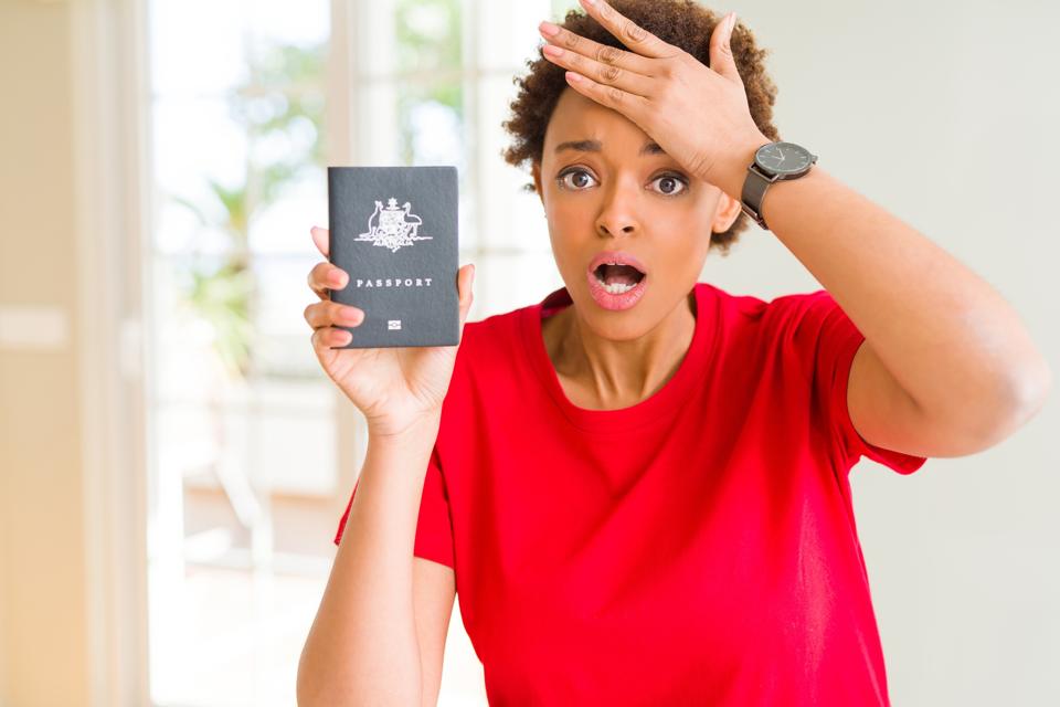 Young african american woman holding Australian passport stressed with hand on head, shocked with shame and surprise face, angry and frustrated. Fear and upset for mistake.