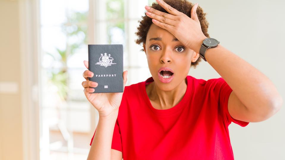 Young african american woman holding Australian passport stressed with hand on head, shocked with shame and surprise face, angry and frustrated. Fear and upset for mistake.